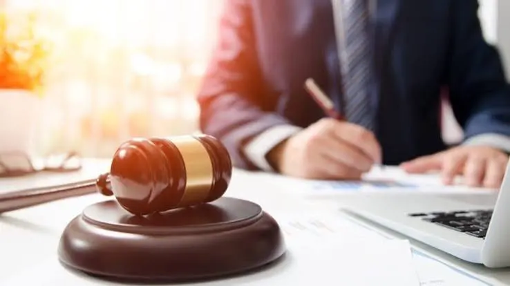 A solicitor writing at a desk with a gavel
