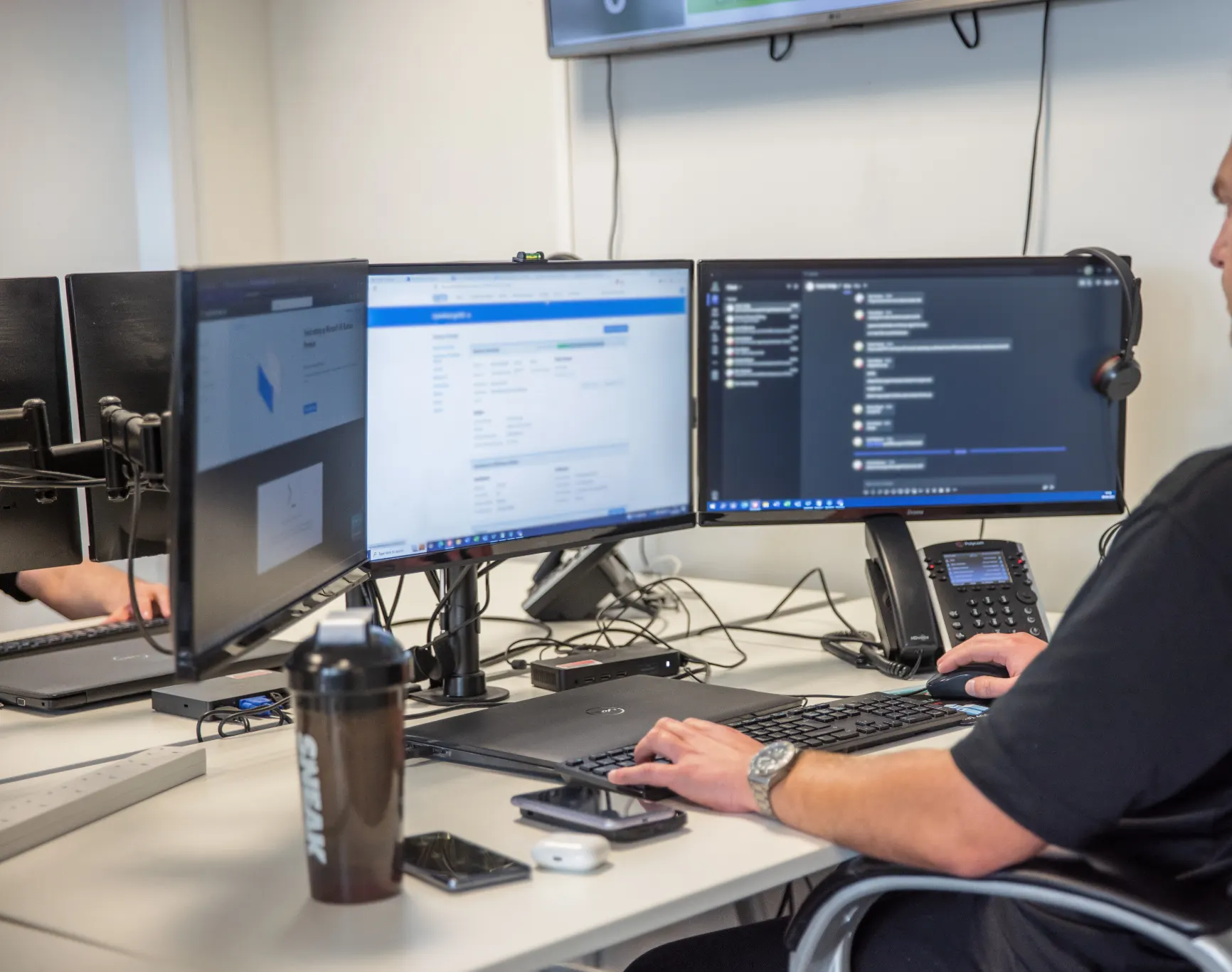 A Technologylab support engineer working at a dual-monitor helpdesk workstation